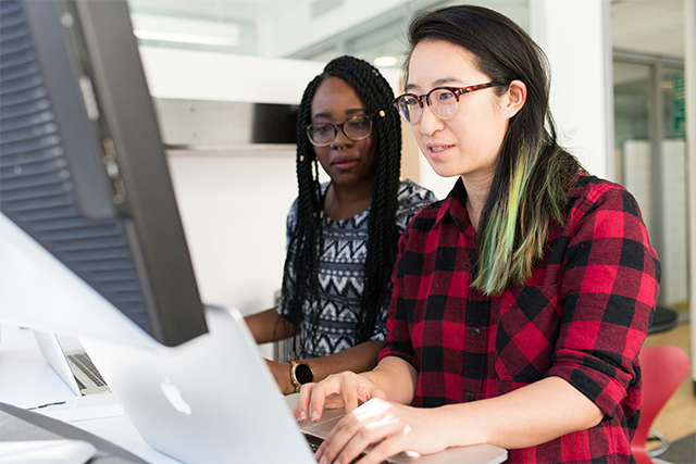 Two people working side by side at a computer.