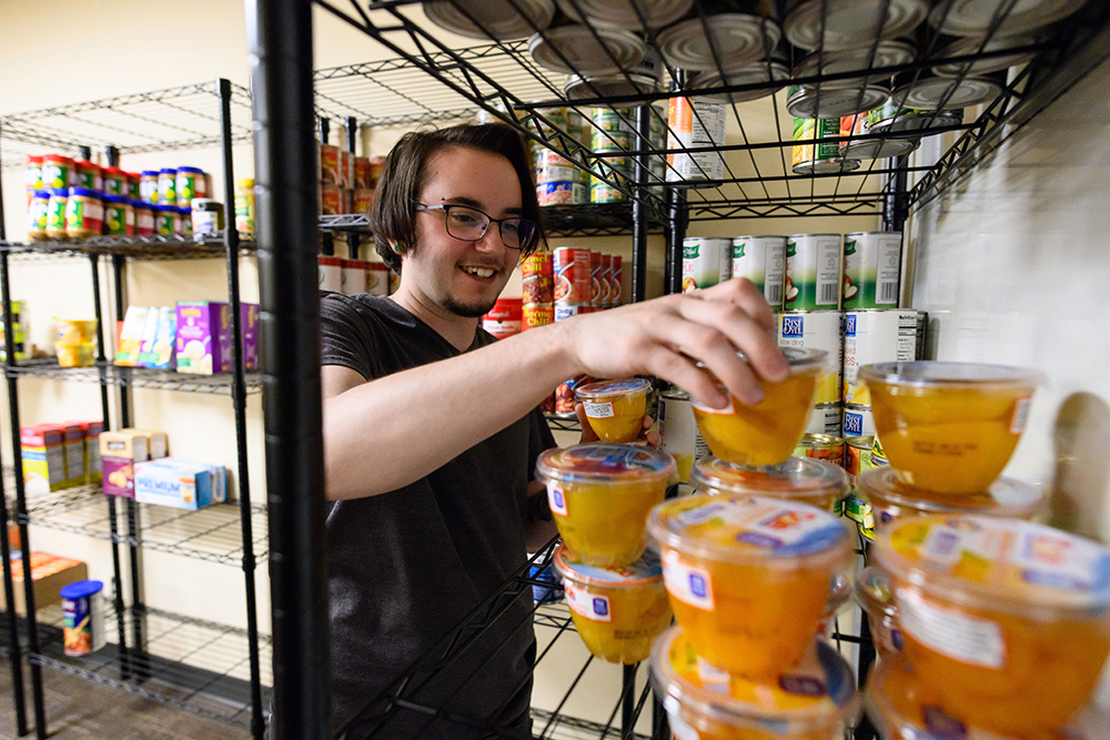 A student grabbing a cup of fruit from a shelf.