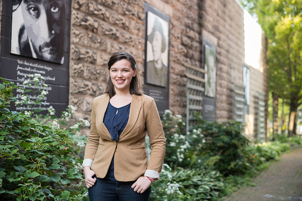 A student in business clothes standing outside a building.