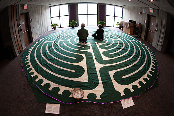 Two people sitting on a labyrinth mat.