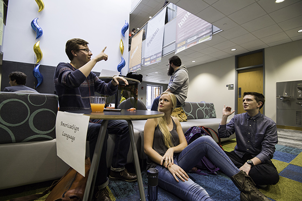 Three students gathered around a couch.