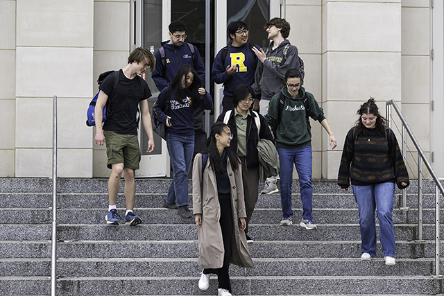 A group of students exiting a building down a set of stairs.