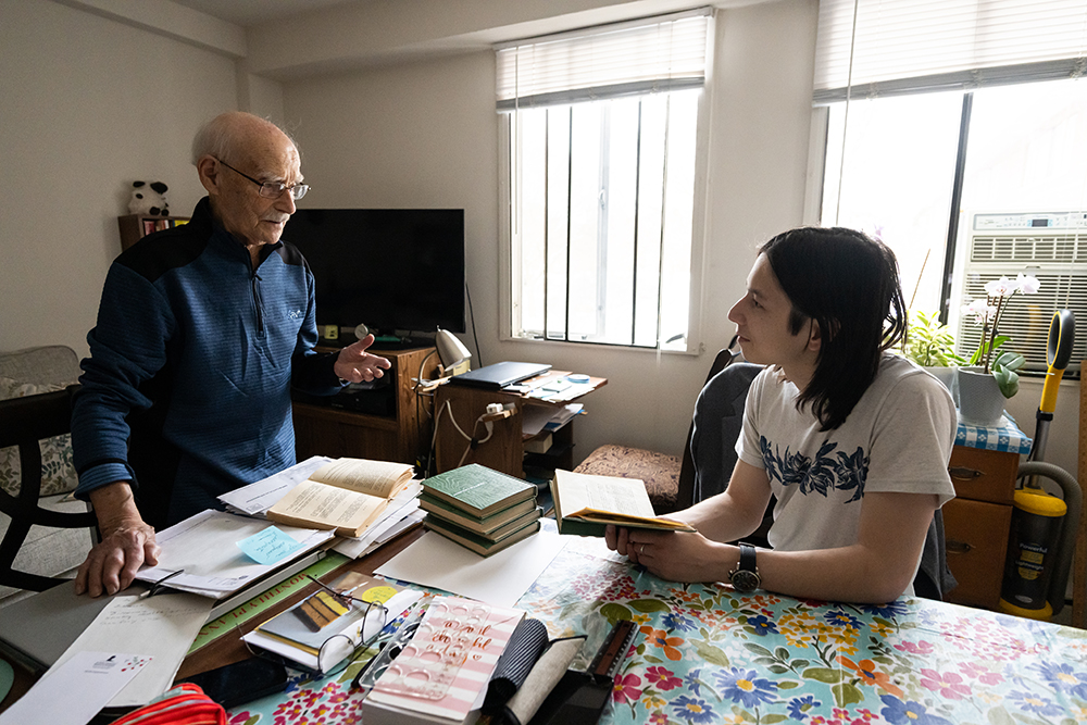 A community member shares cultural knowledge with a student at his kitchen table.