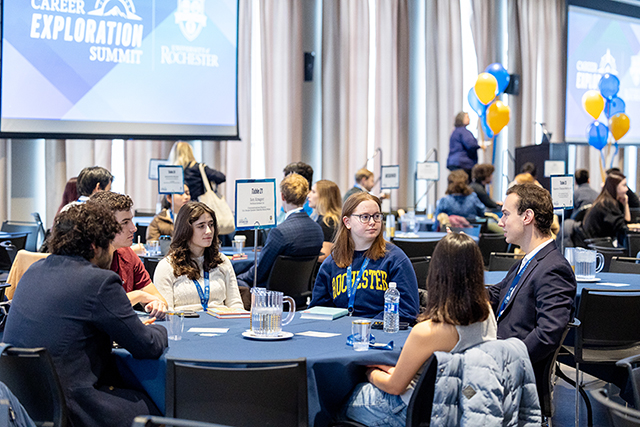 A table of students speaking with an alumnus at the Career Exploration Summit.